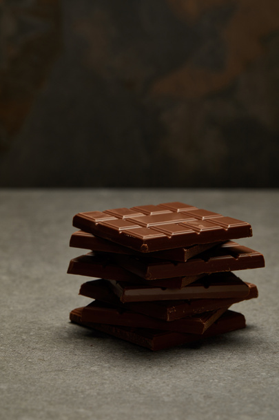 vista de cerca de barras de chocolate apiladas sabrosas dulces sobre fondo gris
  - Foto, imagen