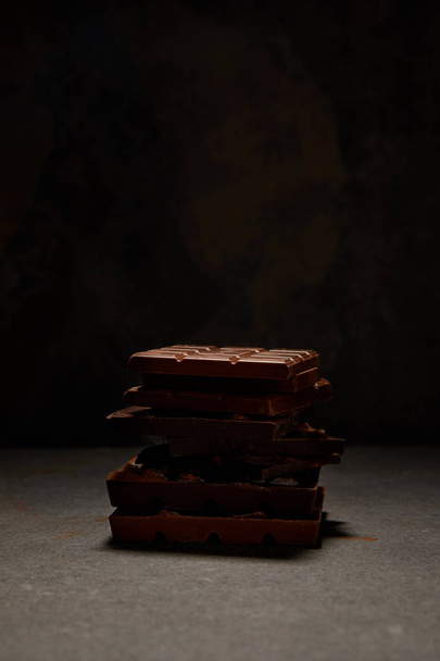close-up view of stacked delicious chocolate pieces on black background - Foto, Imagem