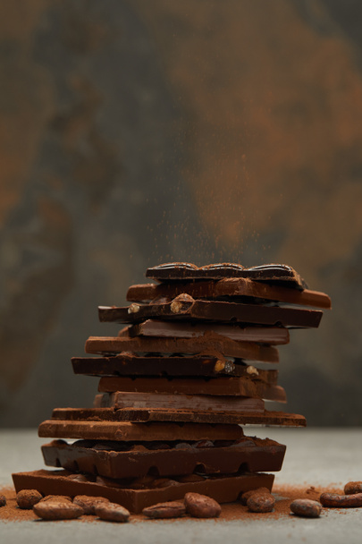 vista de cerca de apiladas deliciosas piezas de chocolate surtidos y nueces en gris
  - Foto, imagen