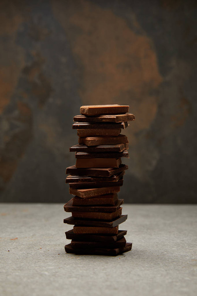 close-up view of stacked delicious tasty chocolate pieces on grey  - Φωτογραφία, εικόνα