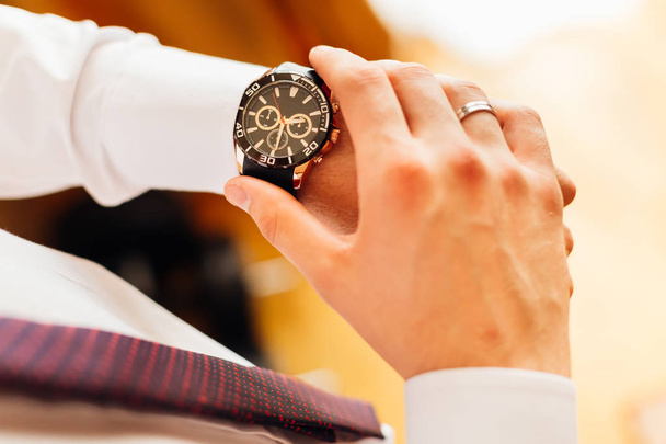 nowoczesny i stylowy zegarek na rękę pana młodego, który patrzy na tarczy zegarka - Zdjęcie, obraz