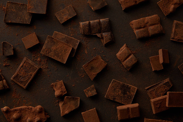 top view of delicious chocolate pieces on black background - Zdjęcie, obraz