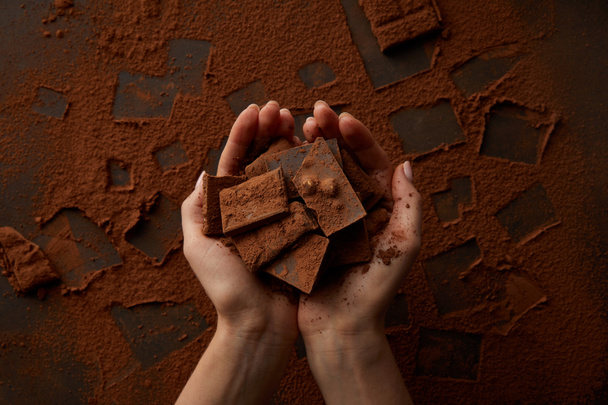 bijgesneden schot van heerlijke chocoladestukjes in menselijke handen - Foto, afbeelding