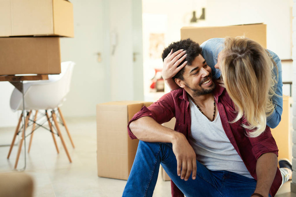 Young happy couple in love moving in new home and unpacking boxes - Zdjęcie, obraz