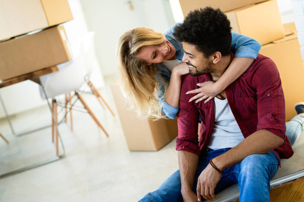 Young happy couple in love moving in new home and unpacking boxes - Fotografie, Obrázek
