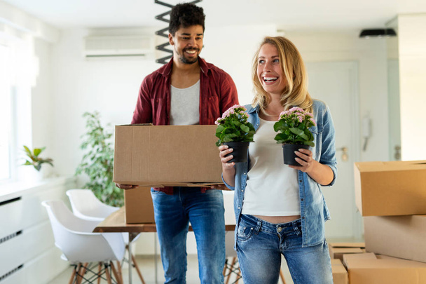 Young happy couple in love moving in new home and unpacking boxes - Zdjęcie, obraz