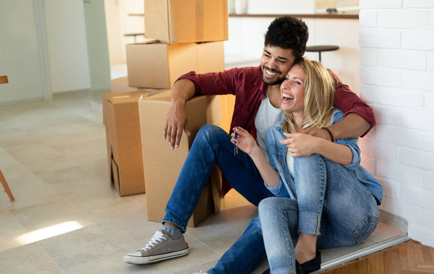 Young couple in love unpacking cardboard boxes at new home moving in concept - 写真・画像