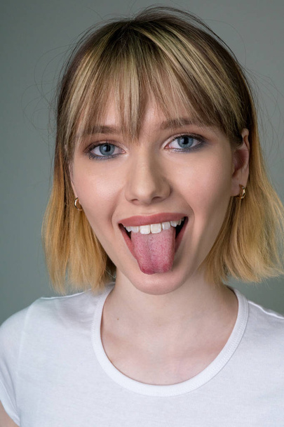 Portrait of a beautiful girl showing the tongue. - Foto, Imagem
