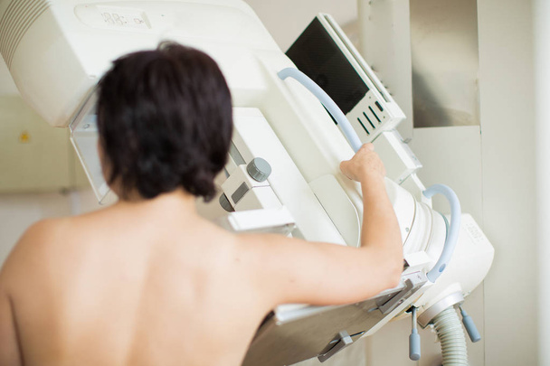 Visão traseira de uma paciente no processo de cuidar do exame de ultra-som da mama dentro de casa
 - Foto, Imagem