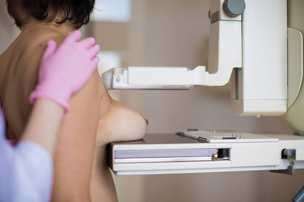 Close-up the breast specialist carrying out the ultrasound examination of the breast of a patient indoors - 写真・画像