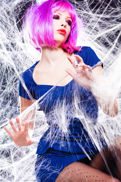 sexy woman with purple wigh and intense make-up trapped in a spider web - fashion shoot - Photo, Image