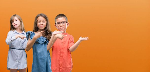 Group of boy and girls kids over orange background very happy pointing with hand and finger - Photo, Image