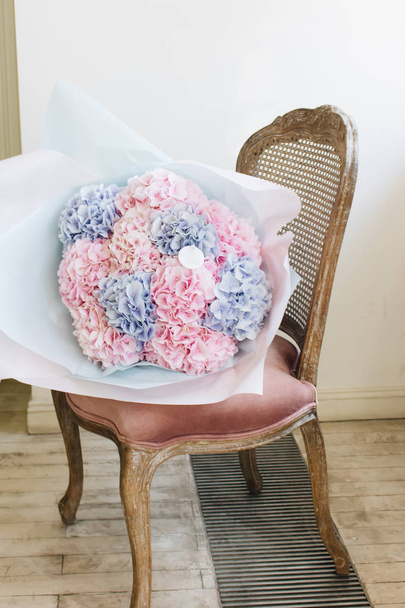 beautiful spring bouquet of tender pink ranunculus flowers on chair, elegant floral decoration  - Photo, Image