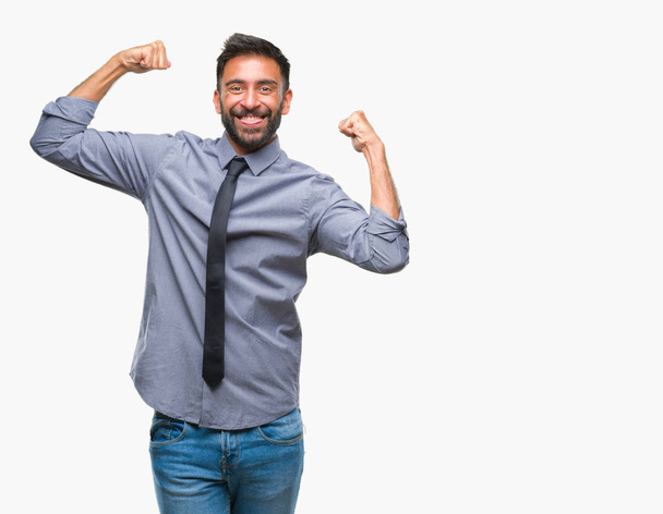 Volwassen Spaanse zakenman op geïsoleerde achtergrond armen spieren glimlachend trots tonen. Fitness concept. - Foto, afbeelding