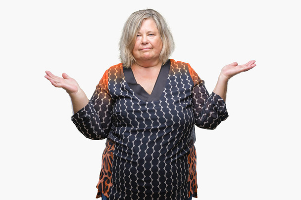 Senior plus size caucasian woman over isolated background clueless and confused expression with arms and hands raised. Doubt concept. - Photo, Image