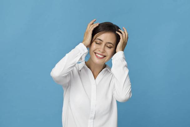 Portrait of a pretty smiling woman with white shirt posing isolated on a blue background - Photo, image