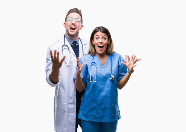 Jeune couple de médecin et chirurgien sur fond isolé célébrant fou et fou de succès avec les bras levés et les yeux fermés hurlant excités. Concept gagnant
 - Photo, image