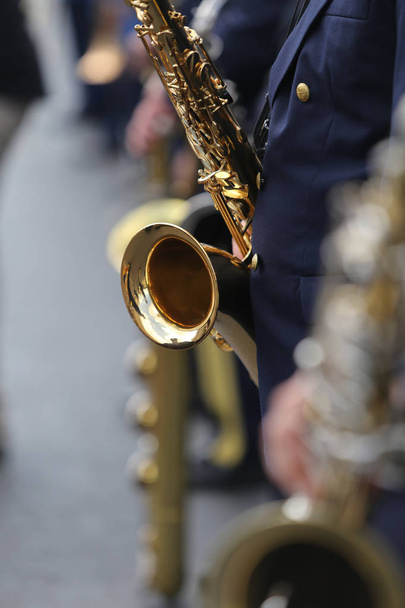 Detalles de un miembro de la banda de desfile militar sosteniendo un saxofón
 - Foto, Imagen