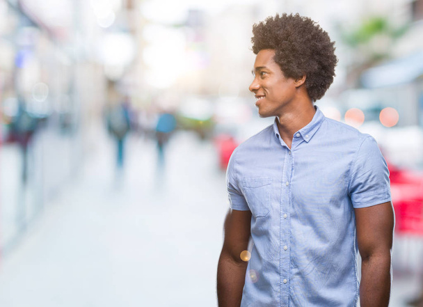Homem afro-americano sobre fundo isolado olhando para o lado com sorriso no rosto, expressão natural. Rindo confiante
. - Foto, Imagem