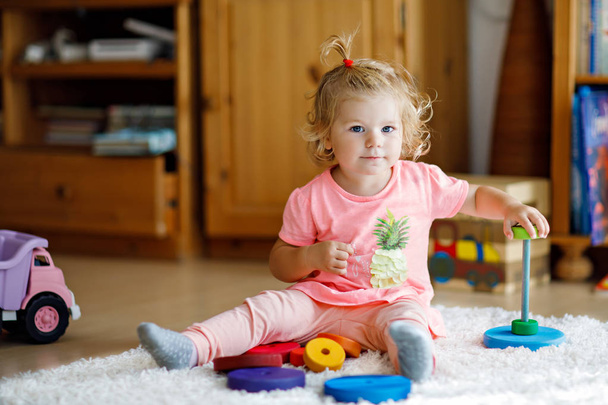 Schattig leuk mooie babymeisje speelt met educatieve kleurrijke houten rainboy speelgoed piramide - Foto, afbeelding