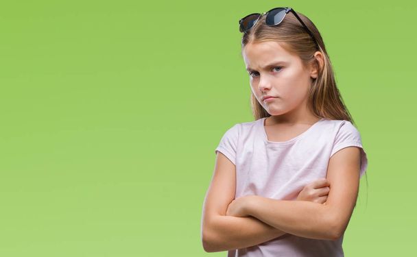 Young beautiful girl wearing sunglasses over isolated background skeptic and nervous, disapproving expression on face with crossed arms. Negative person. - Foto, Bild