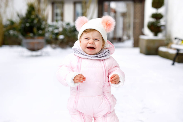 冬に屋外で最初の一歩を踏み出す愛らしい小さな赤ちゃんの女の子。かわいい幼児歩くことを学ぶ. - 写真・画像