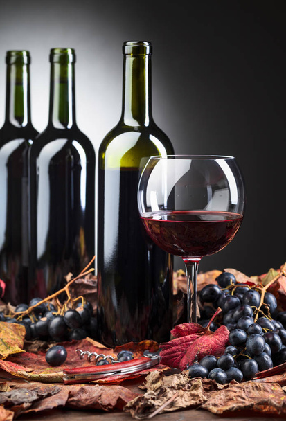 Piros borosüvegek, sötét szőlő és száraz szőlőlevél . - Fotó, kép