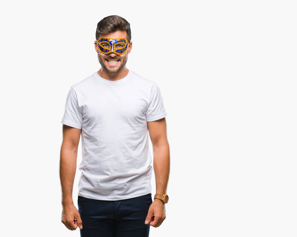 Young handsome man wearing carnival mask over isolated background with a happy and cool smile on face. Lucky person. - Zdjęcie, obraz