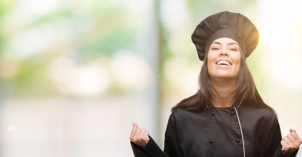 Mladý kuchař hispánský žena nosí uniformě kuchař křičí hrdá a slaví vítězství a úspěch, velmi rádi, fandění emoce - Fotografie, Obrázek