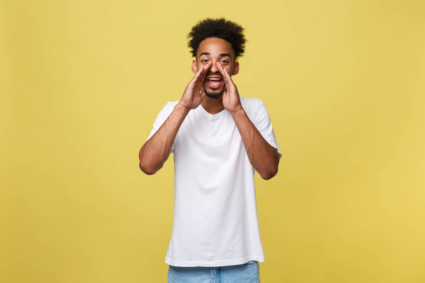 positive young black guy, student, worker employee screams mouth wide open and putting his hands to his face as mouthpiece. Portrait on white background in casual clothing. - Foto, Imagem