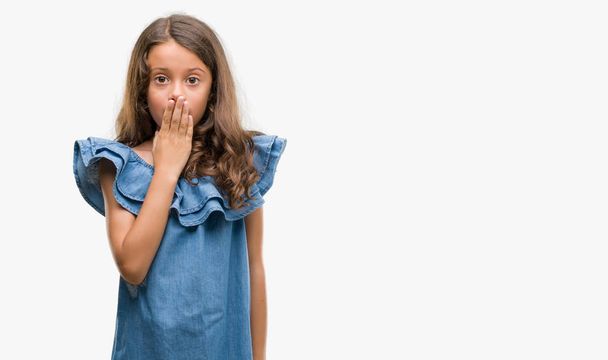 Brunetka hispánský dívka na sobě Džínové šaty kryt ústa rukou šokován studem za chybu, výraz strachu, strach v tichosti, tajné koncept - Fotografie, Obrázek