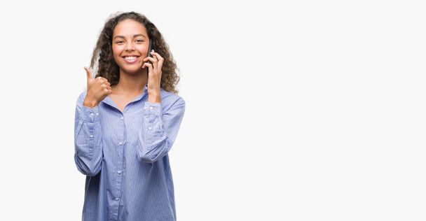 Young hispanic woman using smartphone happy with big smile doing ok sign, thumb up with fingers, excellent sign - Fotoğraf, Görsel