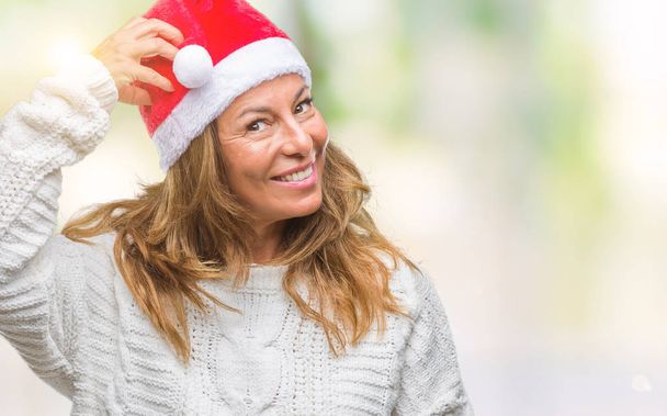 Středním věku senior hispánské ženy nosí vánoční čepice izolované pozadí mást a zajímat o otázku. Nejisté s pochybností, myšlení s rukou na hlavu. Zamyšlená koncepce. - Fotografie, Obrázek