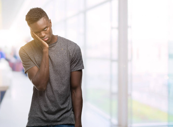 グレー t シャツ思考を身に着けている若いアフリカ系アメリカ人は疲れや交差腕を持つうつ病問題と退屈. - 写真・画像