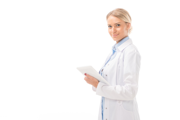 happy young female doctor working with tablet and looking at camera isolated on white - Zdjęcie, obraz