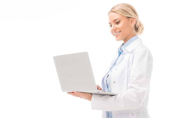 Gelukkig jonge vrouwelijke arts werken met laptop geïsoleerd op wit - Foto, afbeelding