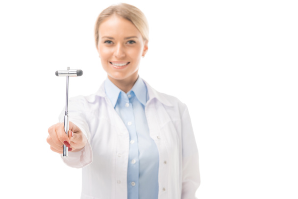 smiling young female neurologist holding reflex hammer and looking at camera isolated on white - Foto, immagini