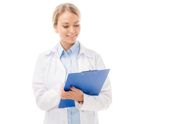 smiling young female doctor writing in clipboard isolated on white - 写真・画像