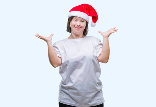 Young adult woman with down syndrome wearing christmas hat over isolated background celebrating crazy and amazed for success with arms raised and open eyes screaming excited. Winner concept - Foto, Imagen