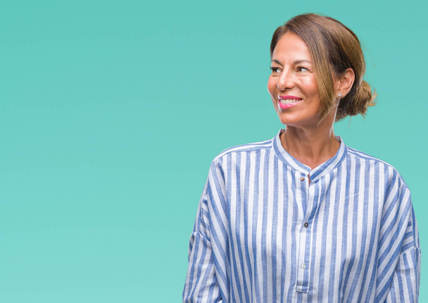 Middle age senior hispanic woman over isolated background looking away to side with smile on face, natural expression. Laughing confident. - Photo, Image