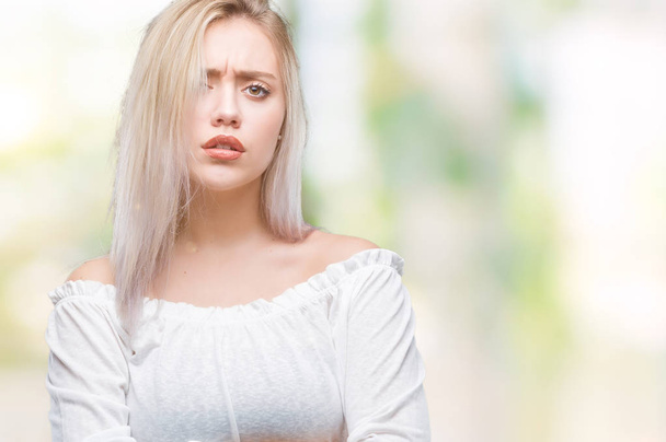 Young blonde woman over isolated background skeptic and nervous, disapproving expression on face with crossed arms. Negative person. - Photo, image