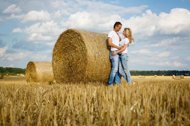 Young romantic loving couple hugging standing in wheat field at sunrise - Фото, изображение