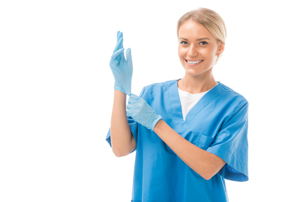 happy young nurse putting on rubber gloves isolated on white - Фото, зображення