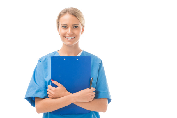 glücklich junge Krankenschwester mit Klemmbrett und Blick auf Kamera isoliert auf weiß - Foto, Bild