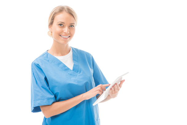 felice giovane infermiera che lavora con tablet digitale e guardando la fotocamera isolata su bianco
 - Foto, immagini