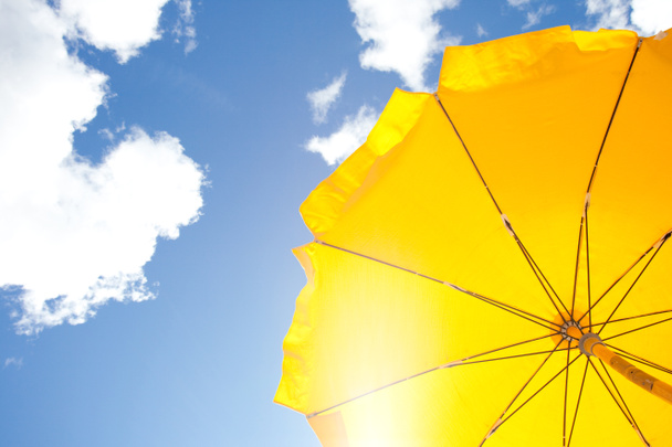 keltainen sateenvarjo sinisellä taivaalla pilvillä
 - Valokuva, kuva