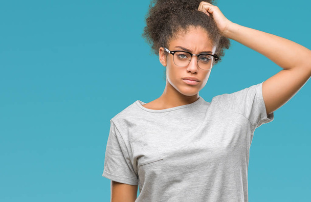 Jeune femme afro-américaine portant des lunettes sur fond isolé confondre et s'interroger sur la question. Incertain avec le doute, pensant la main sur la tête. Concept pensif
. - Photo, image