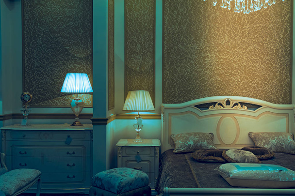 Tankowany podwójne łóżko z fiolką pokrycie poduszki z szafki i lampki z kryształowy żyrandol - Zdjęcie, obraz