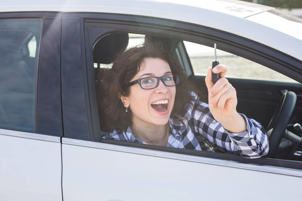 Νεαρή γυναίκα ευτυχισμένη που δείχνει το κλειδί του νέου αυτοκινήτου - Φωτογραφία, εικόνα