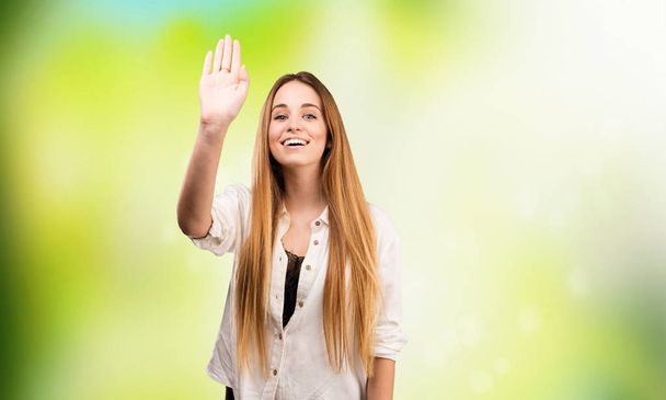 pretty young woman greeting on blurred green background - Photo, Image
